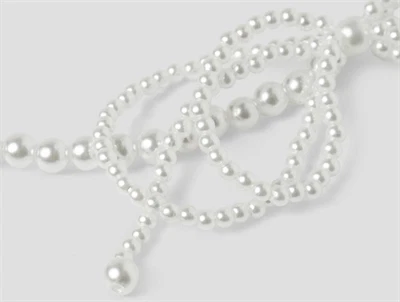 Nærbillede af smykkesæt fra Name It i hvid med perler og sløjfe